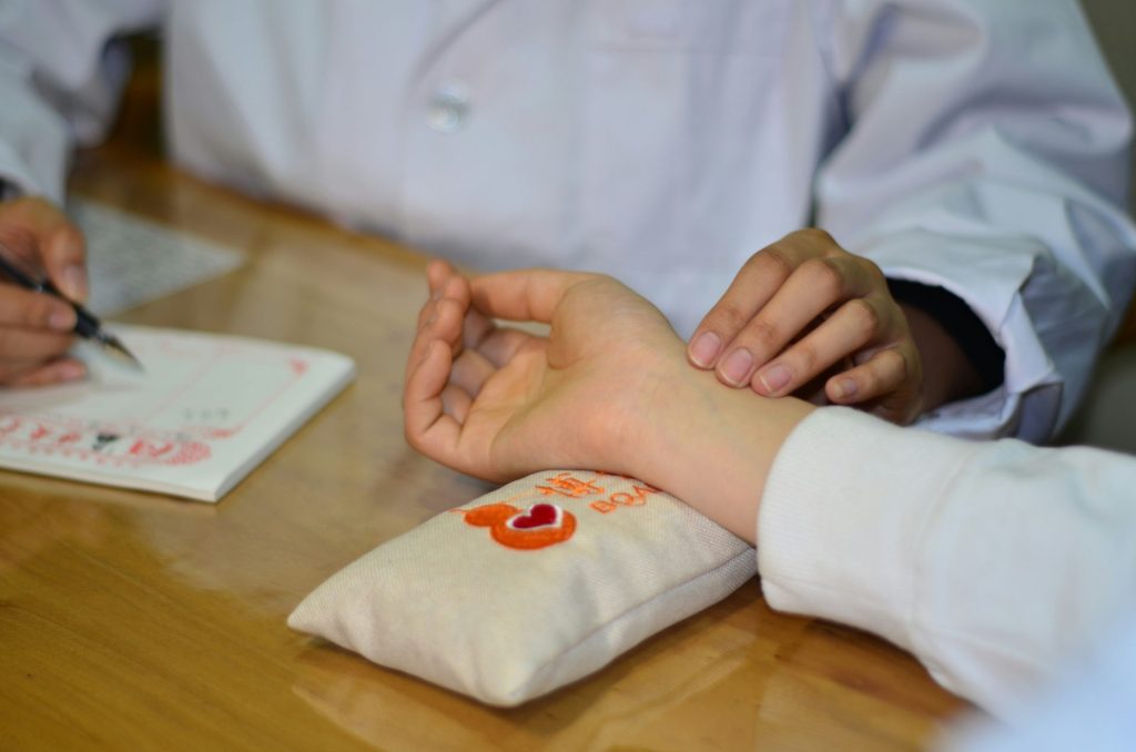 person in white long sleeve shirt with red and white heart tattoo on right hand